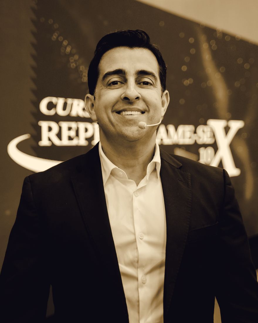 Retrato de Isaac Santos sorrindo, de terno, com microfone de cabeça